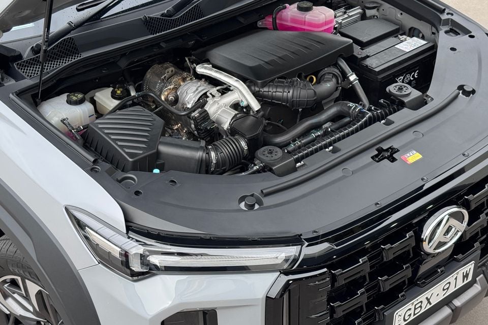 The open engine bay of a white LDV D90 SUV, showing the diesel engine and surrounding components.