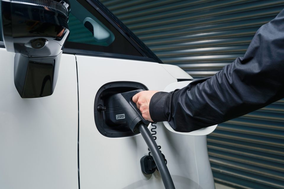 A person plugging an EV charging cable into the charge port of a white LDV eDeliver 5 van