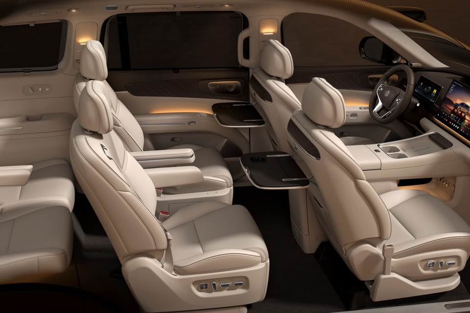 Cream leather cabin of the Leapmotor D19 with captain's chairs, fold-out tables, steering wheel and dual dashboard screens, seen from the side
