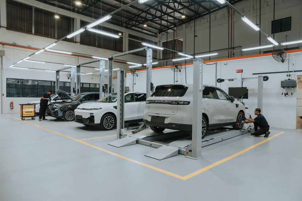 Technicians servicing Leapmotor electric vehicles inside a modern dealership workshop, with cars on Rotary Lift hoists and a tool trolley nearby.