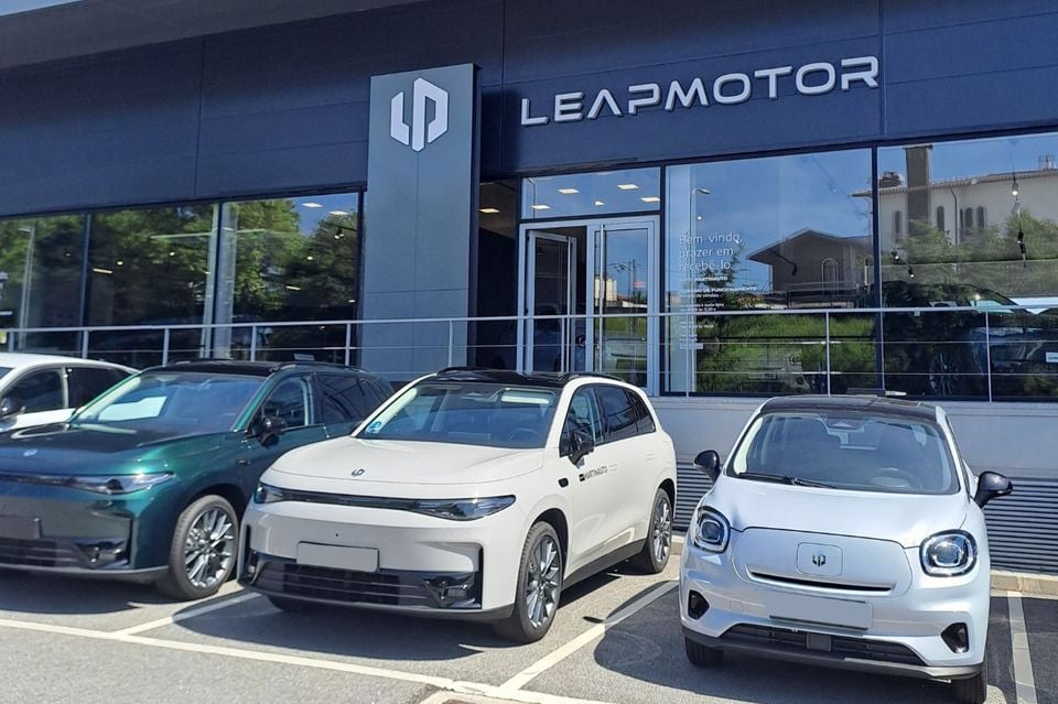 Three Leapmotor electric vehicles parked outside a Leapmotor dealership, including a white SUV and a small silver city car