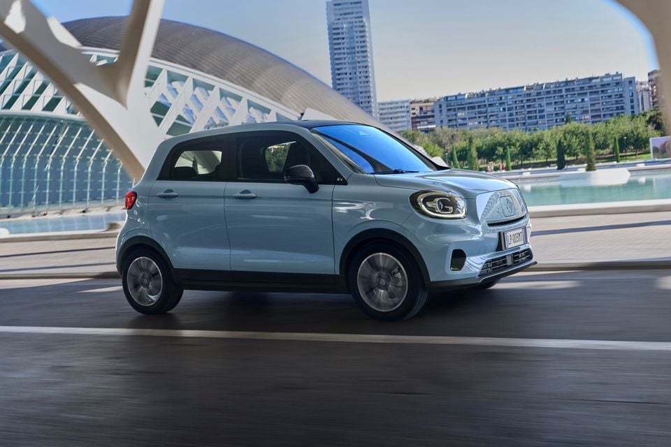 A light blue Leapmotor T03 small electric hatchback driving through a modern city setting