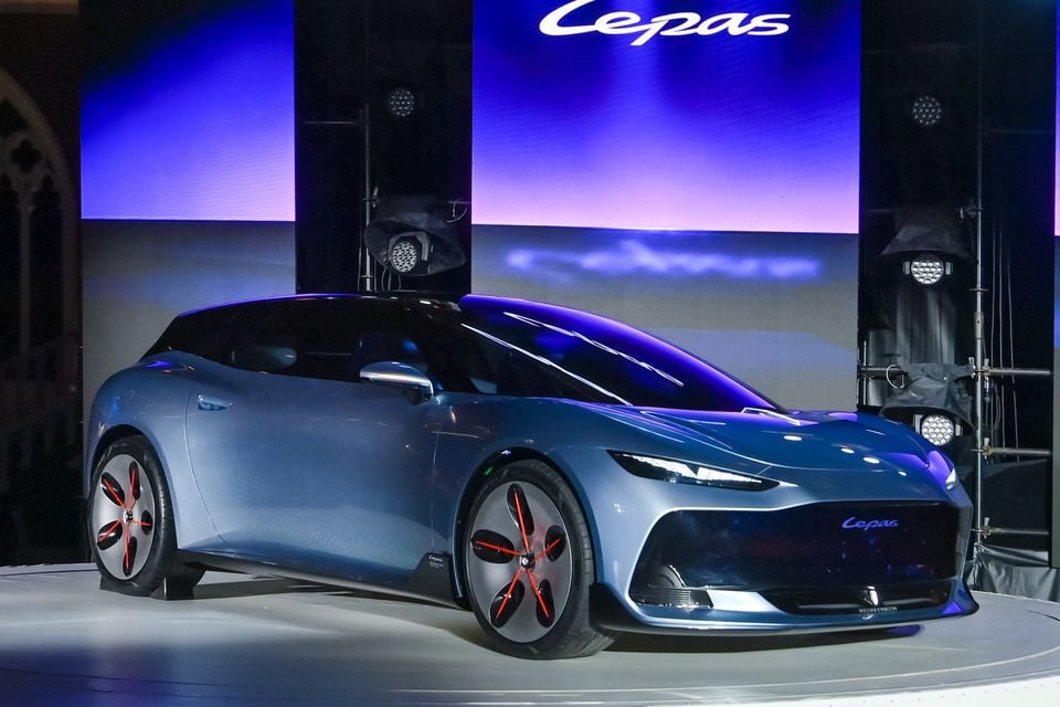 A pale blue Lepas concept car with a shooting brake-style body and red-accented wheels, displayed on a stage at its launch event