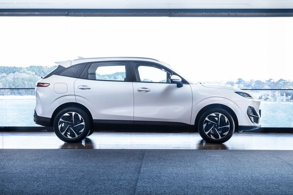 A white Leapmotor C10 SUV seen from the side, displayed indoors with a waterfront view in the background.