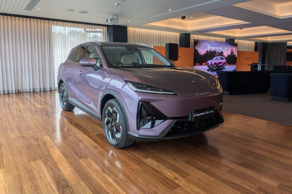 A purple Cepas L6 EV electric SUV displayed indoors at a launch event, seen from the front-side angle