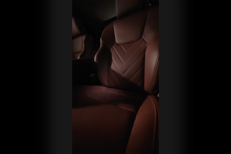 Brown leather rear seats with chevron stitching detail inside a Lexus NX, shown in a dimly lit teaser image