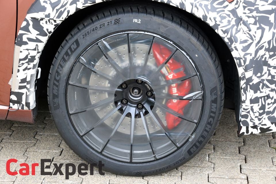 Close-up of a 21-inch Michelin Pilot Sport tyre and multi-spoke dark alloy wheel with red brake calipers on a camouflaged Lexus RX Morizo RR prototype