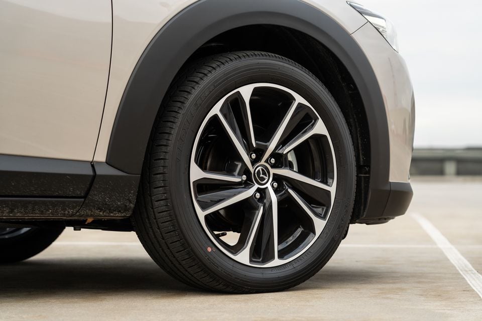 Close-up of a Mazda CX-3 alloy wheel with a black and machined finish, showing the Mazda badge on the centre cap