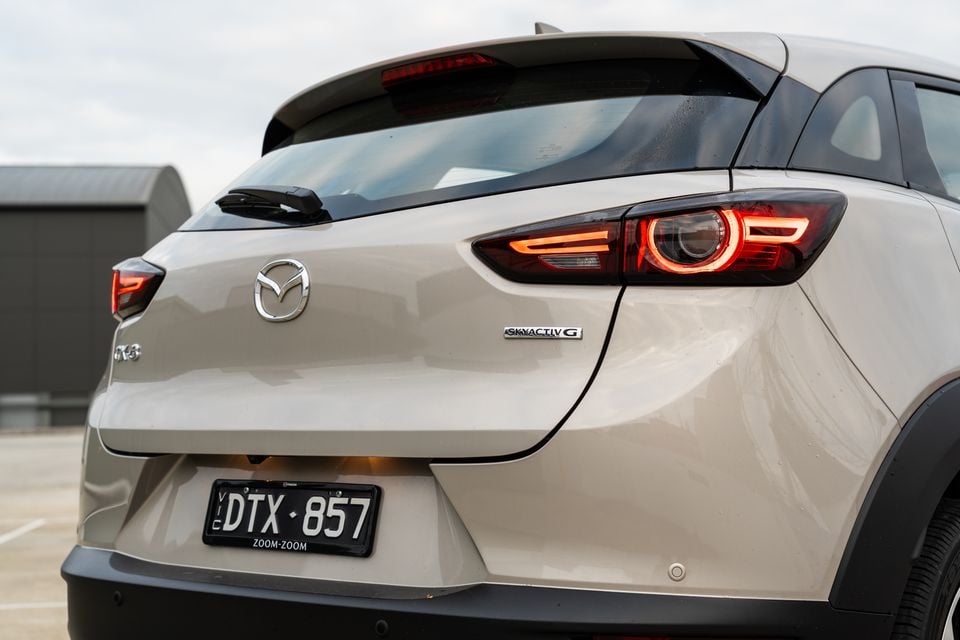Rear of a beige Mazda CX-3 SUV with Skyactiv-G badging and LED tail lights, seen in a car park