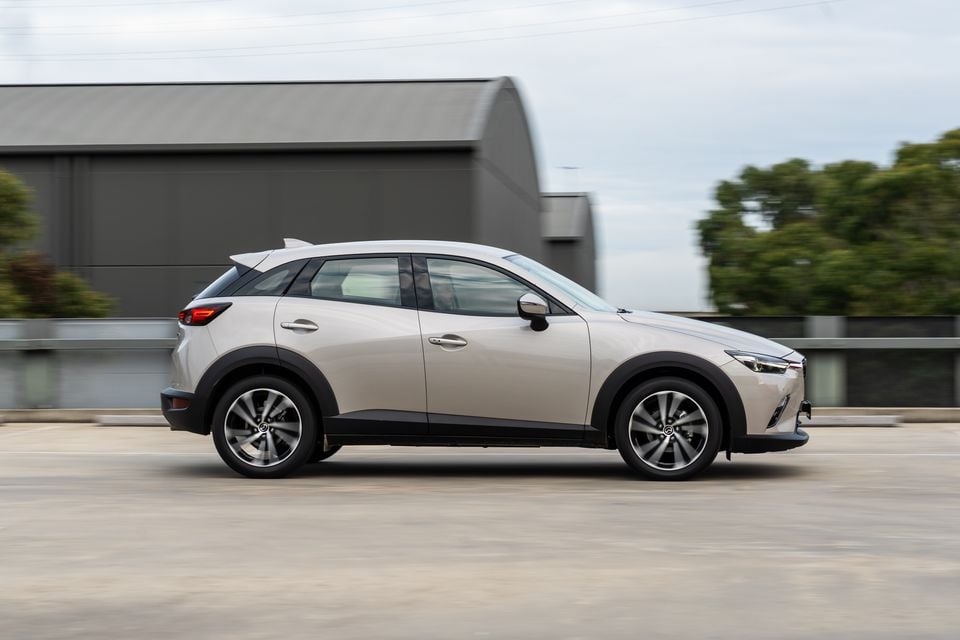 A silver Mazda CX-3 small SUV seen from the side while driving on a road