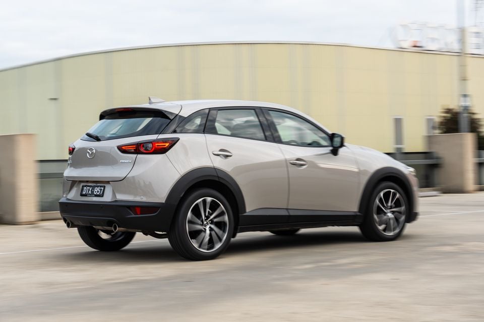 A silver Mazda CX-3 SUV seen from the rear three-quarter angle while driving in an urban area