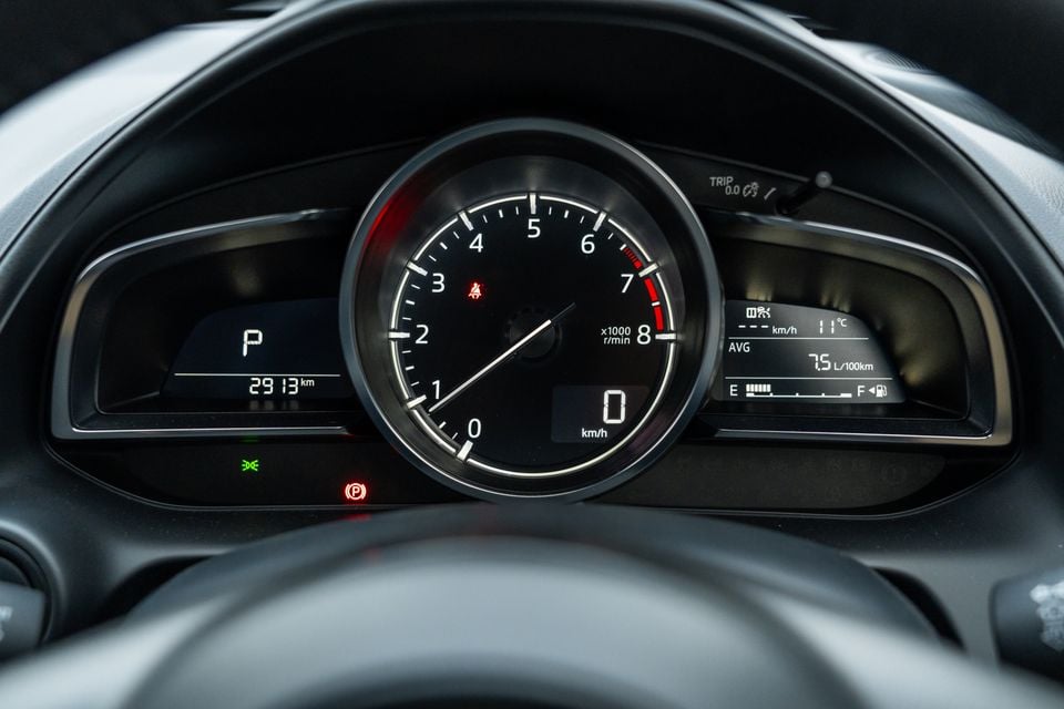 Close-up of the instrument cluster in a Mazda CX-3, showing the tachometer, digital speedometer reading 0 km/h, odometer at 2913 km, and trip computer displaying 7.5L/100km average fuel consumption