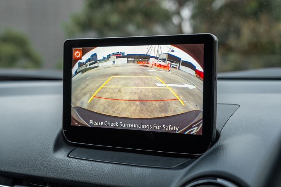 Mazda CX-3 infotainment screen displaying the reversing camera view with parking guidelines and a safety message