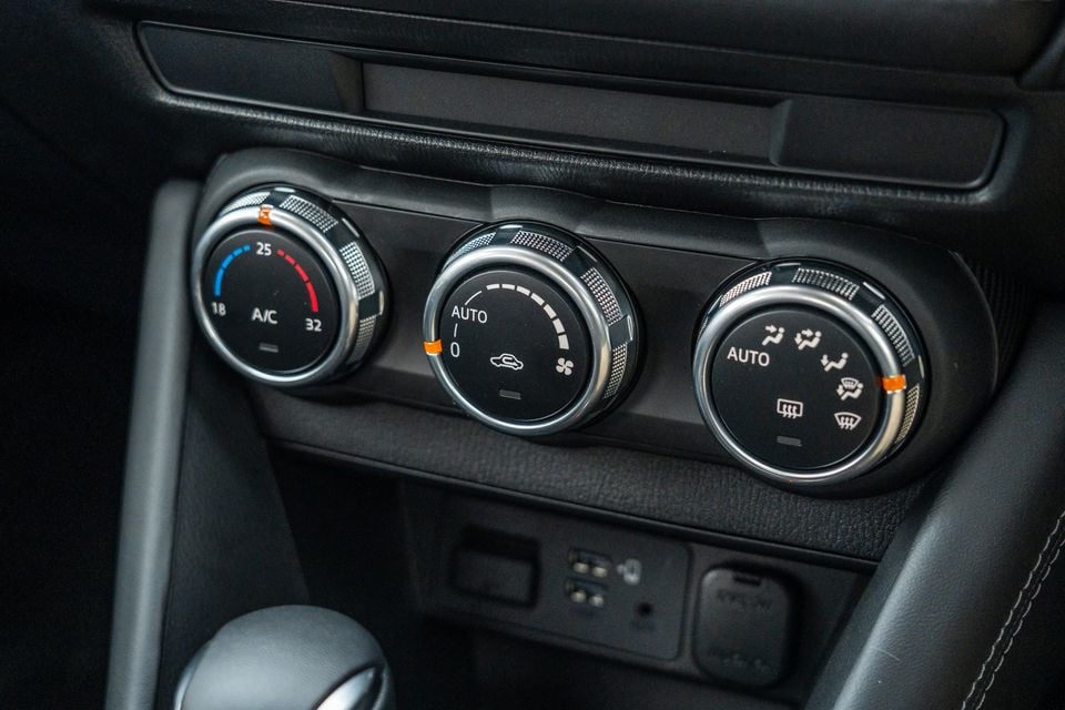 Close-up of the climate control dials inside a Mazda CX-3, showing temperature, fan speed, and airflow mode knobs