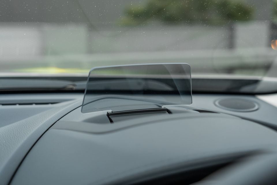 Head-up display unit on the dashboard of a Mazda CX-3, showing a clear reflective screen projecting driver information