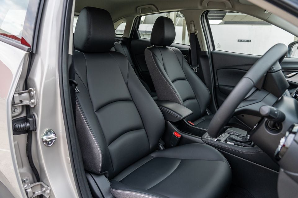 Black leather front seats and centre console of a Mazda CX-3 interior, viewed from the open driver's door
