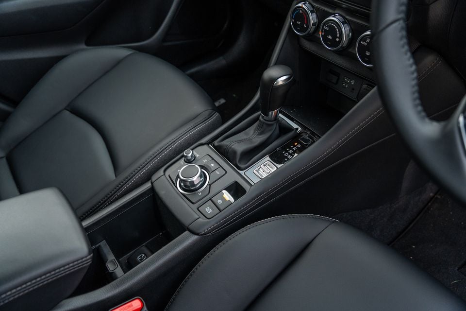 Mazda CX-3 interior showing the centre console with gear shifter, commander control knob, climate controls and leather-trimmed seats