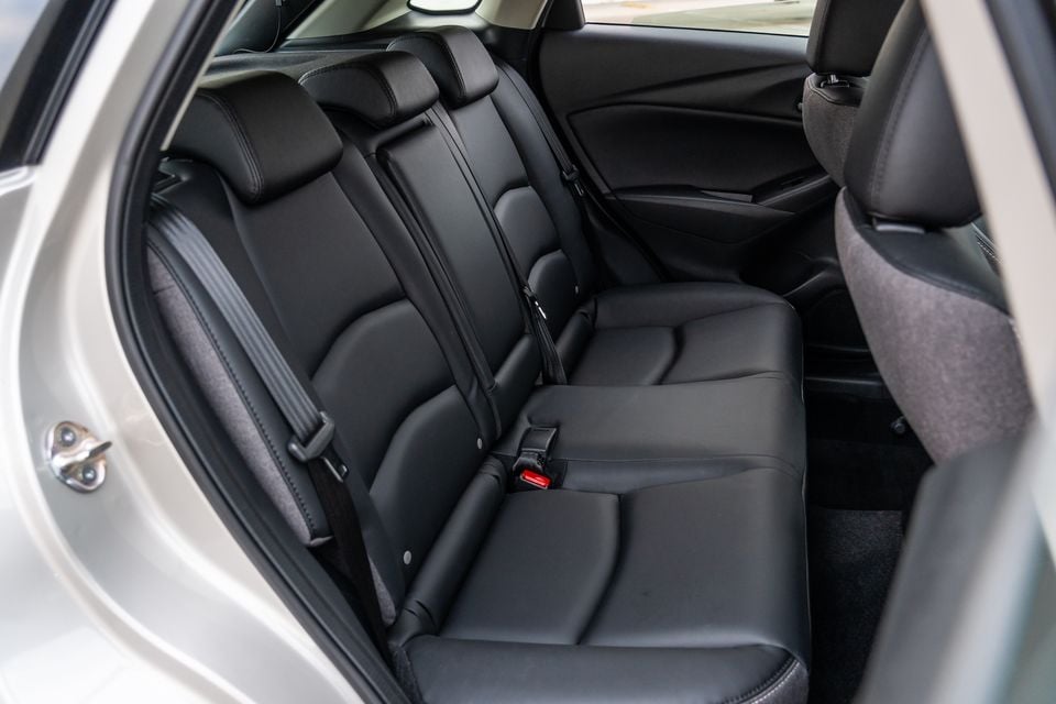 Rear seat interior of a Mazda CX-3 showing black leather bench seat with seatbelts and headrests
