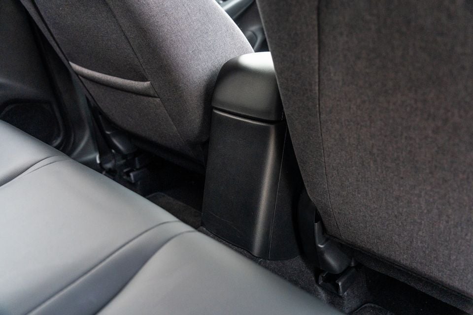 Close-up of the rear seat base and seatback junction area inside a Mazda CX-3, showing fabric upholstery and black plastic trim details