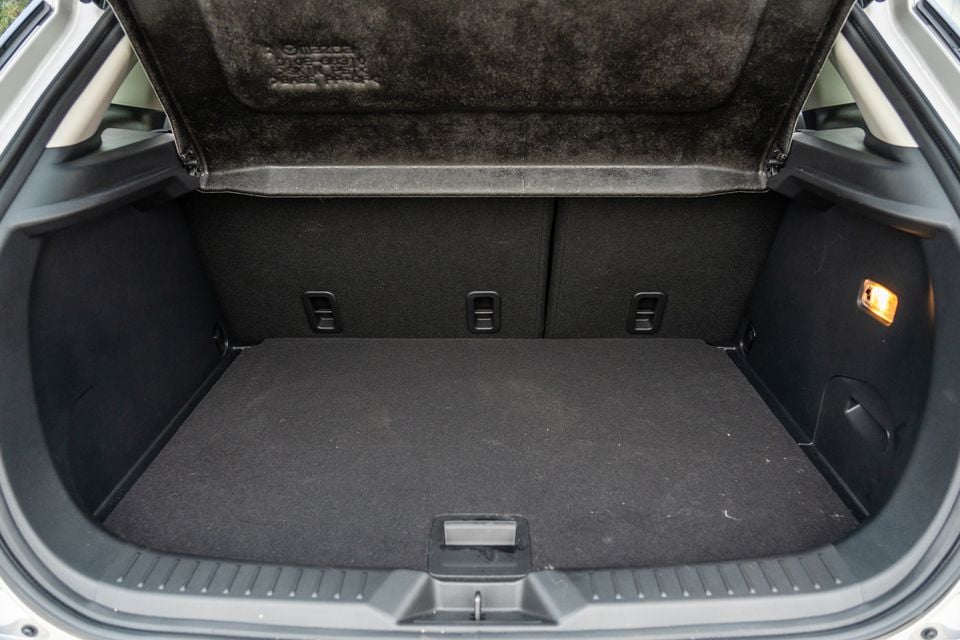 Open boot of a Mazda CX-3, showing a flat carpeted cargo area with rear seat fold-down levers and a boot light