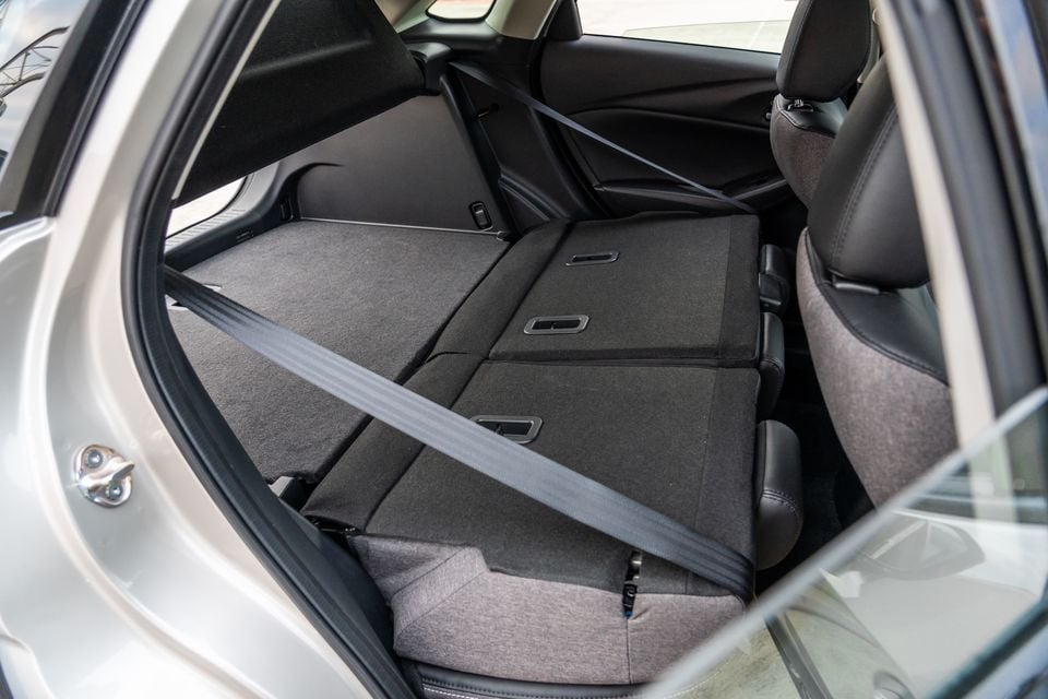 Rear seats folded flat inside a Mazda CX-3, viewed through the open rear door showing the expanded cargo area