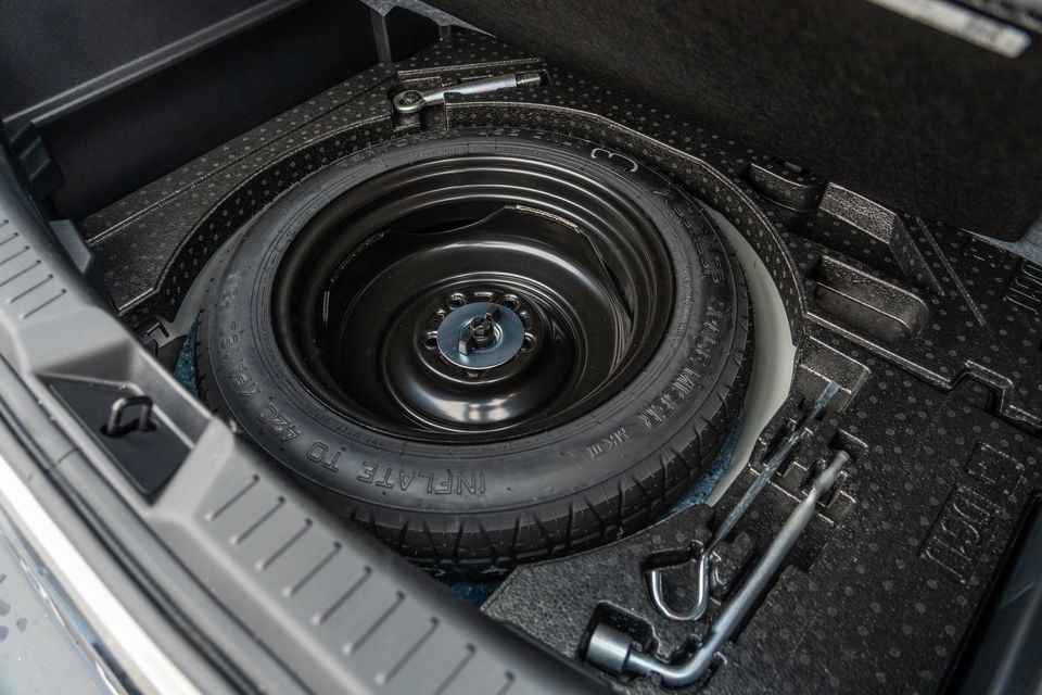 Spare space-saver tyre stored in the under-floor compartment of a Mazda CX-3 boot, with a jack and wheel brace visible