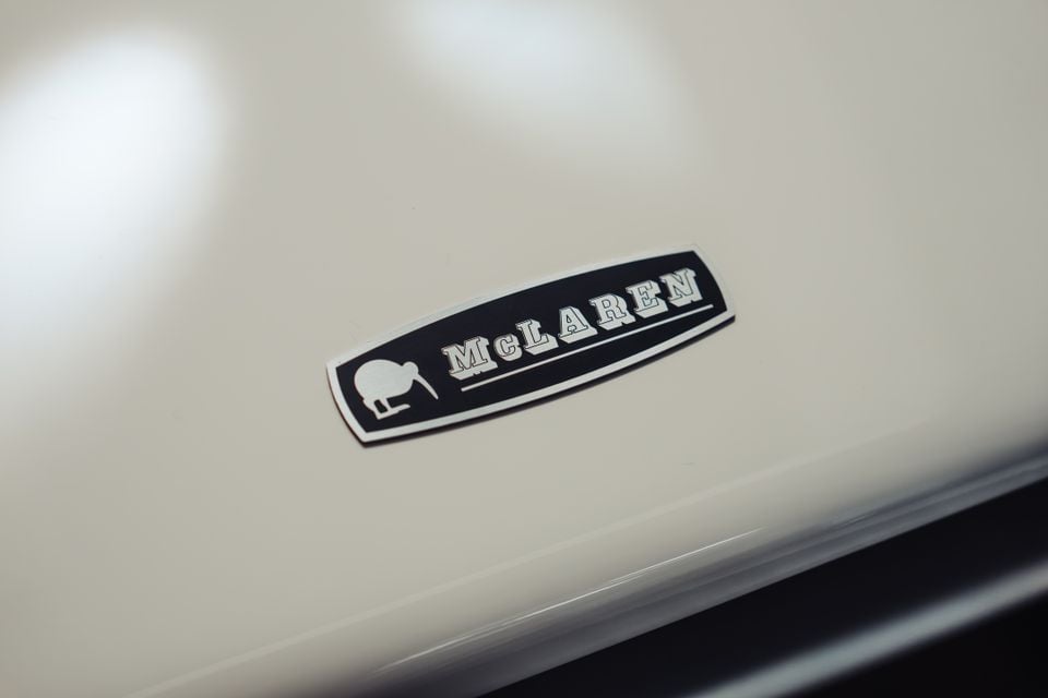 Close-up of a McLaren badge featuring a kiwi bird icon on the bonnet of a white car