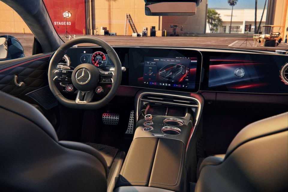 Interior of a Mercedes-AMG GT 53 4-Door Coupe showing the AMG steering wheel, dual widescreen displays with dynamics settings, centre console controls, and sport pedals