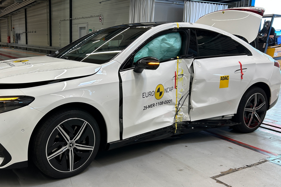 A white Mercedes-Benz CLA shown after a Euro NCAP side impact crash test, with significant door damage and deployed curtain airbags visible