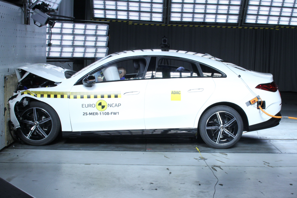 A white Mercedes-Benz CLA sedan after a Euro NCAP frontal crash test, with front-end damage against a barrier, viewed from the side