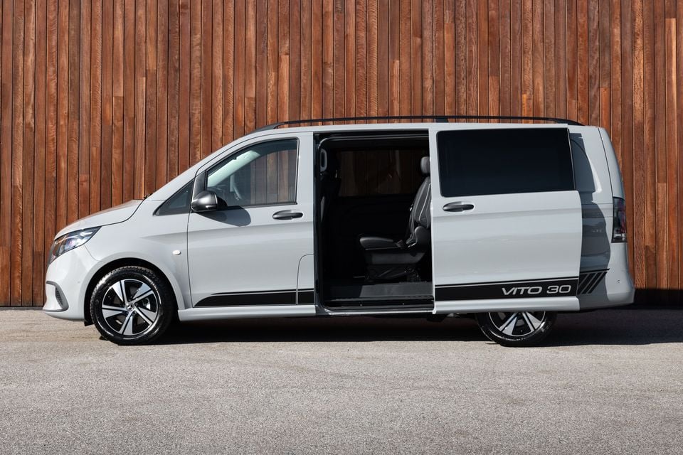 A silver Mercedes-Benz Vito 30th Anniversary edition van seen from the side with the sliding door open, parked in front of a timber wall