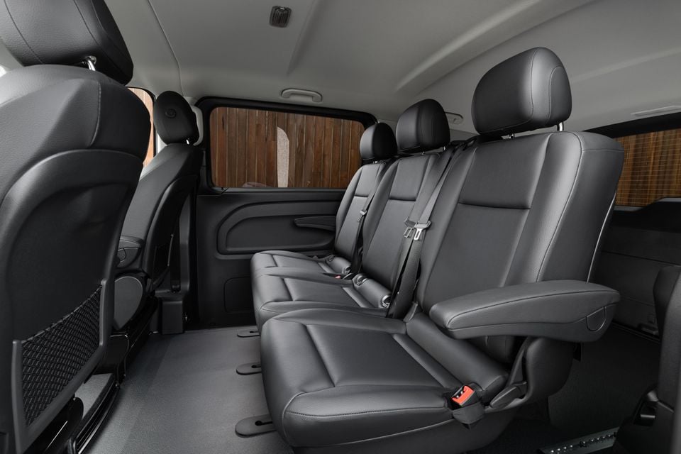 Rear passenger cabin of a Mercedes-Benz Vito showing black leather bench seating with seatbelts and individual headrests