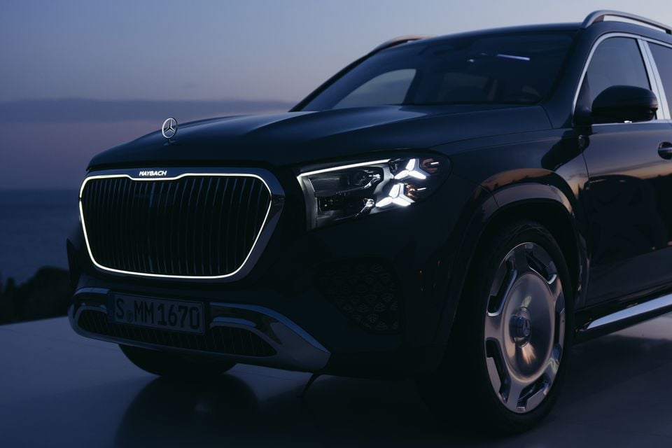 A black Mercedes-Maybach GLS 680 SUV photographed from the front-side at dusk, showcasing its large illuminated grille and star-shaped headlights