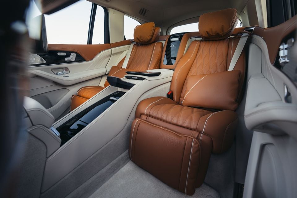 Luxurious tan leather rear seats with diamond-stitch quilting, ottomans, and a centre console in the Mercedes-Maybach GLS 680