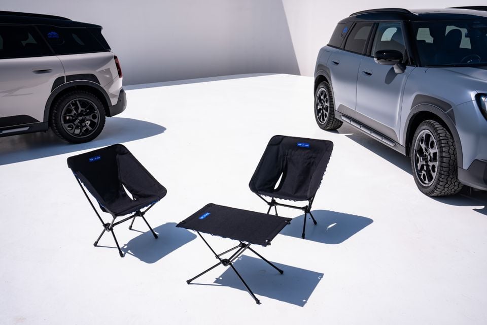 Two Mini Countryman Untamed Edition SUVs parked with black camping chairs and a folding table set up between them