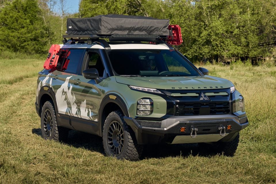 Green Mitsubishi Outlander Diamond Trail Edition SEMA build with roof-top tent, jerry cans and off-road tyres parked in a grassy field