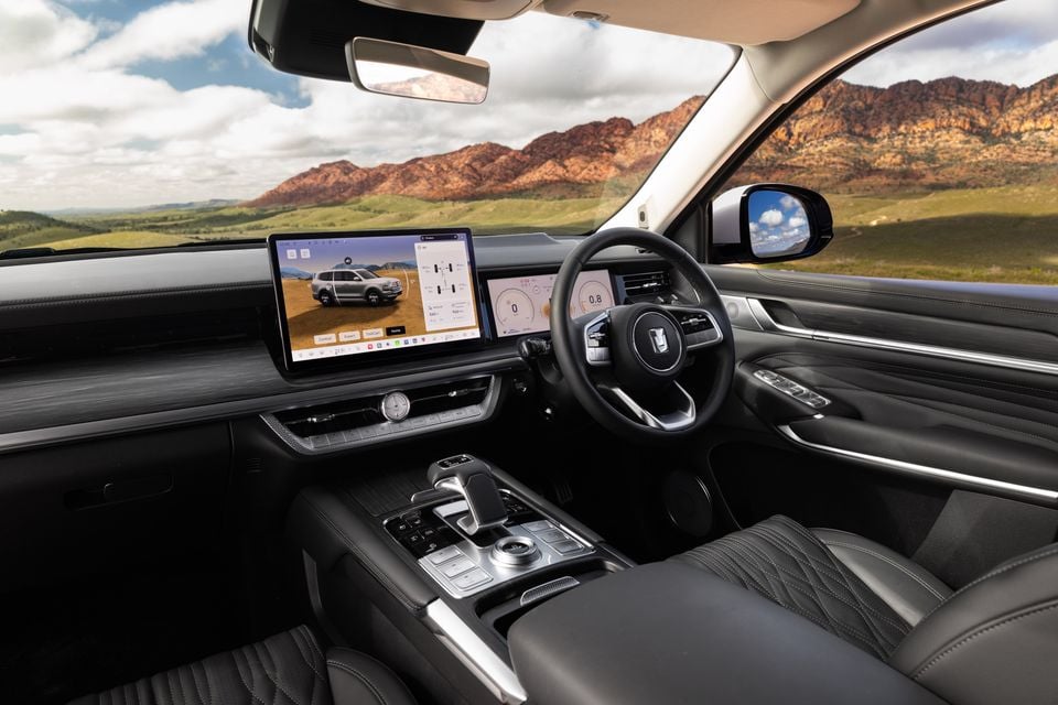 Interior of a GWM Tank 500 showing the dashboard, large central touchscreen infotainment system, digital instrument cluster, steering wheel, and centre console with dark leather trim