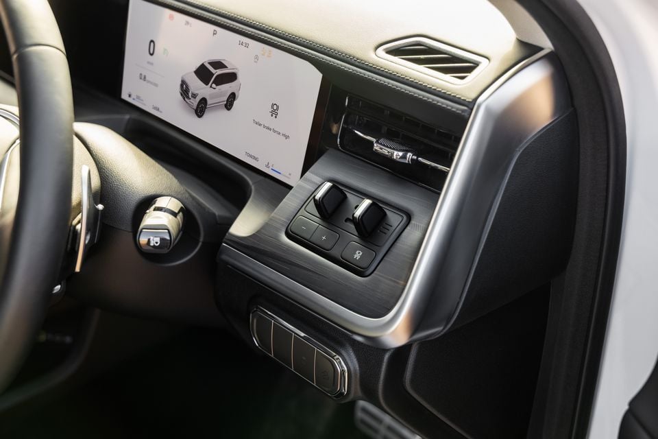 Interior view of a GWM Tank 500 showing the centre console controls, digital instrument cluster displaying towing settings, and gear selector area