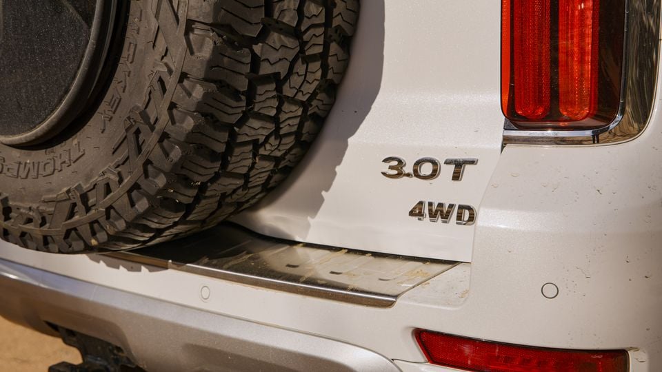 Close-up of the rear of a white GWM Tank 500 4WD SUV showing the 3.0T and 4WD badges alongside a rear-mounted spare wheel and tail light