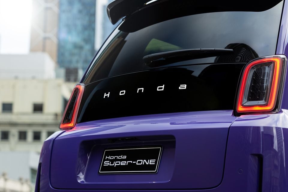 Rear view of a purple Honda Super-One showing the Honda lettering across the rear window and LED taillights in an urban setting