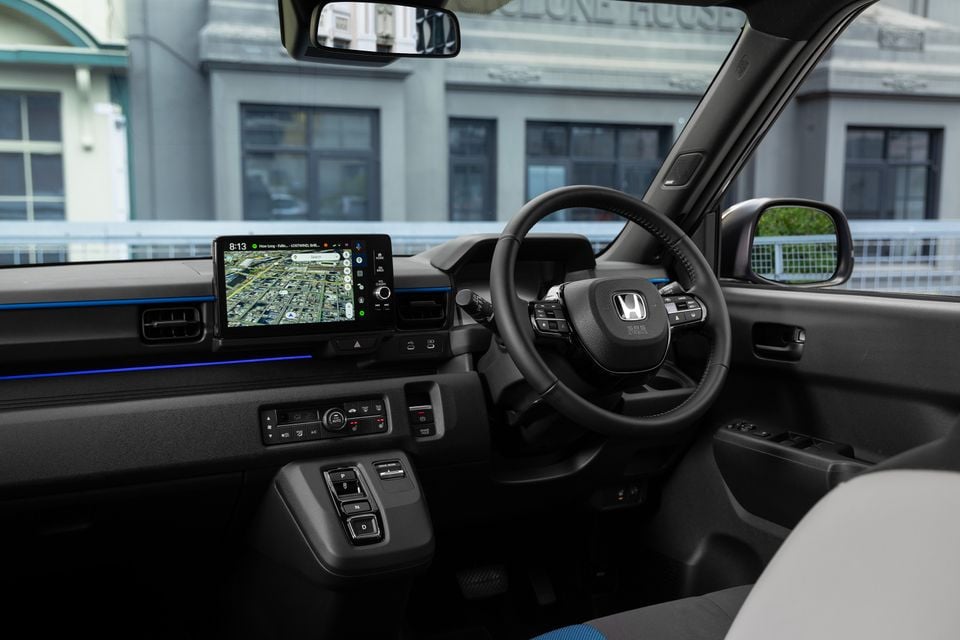 Honda Super One interior showing the dashboard, steering wheel, touchscreen infotainment display with navigation, and centre console with gear selector buttons