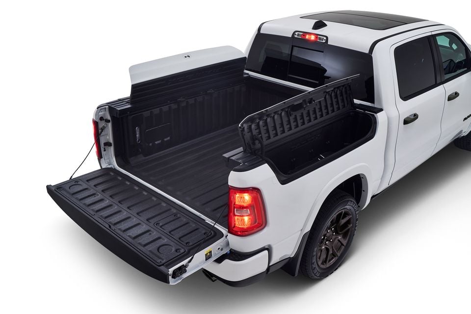 A white Ram 1500 ute seen from the rear with the tailgate lowered, revealing the lined tray bed and multifunction tailgate, on a white background.