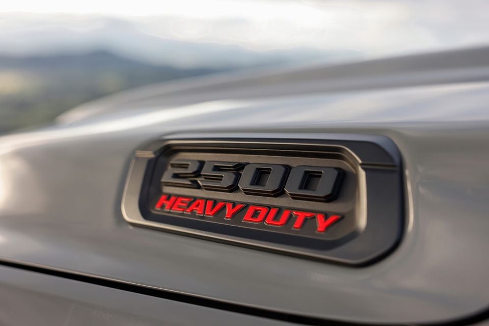 Close-up of the 2500 Heavy Duty badge on a Ram 2500 truck, with red lettering on a dark emblem set into the grey body panel.