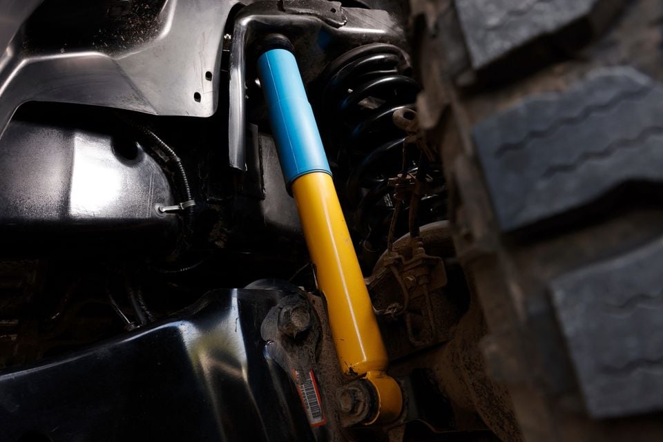 Close-up of a yellow and blue aftermarket shock absorber fitted to the rear suspension of a Ram 2500 Warlock truck