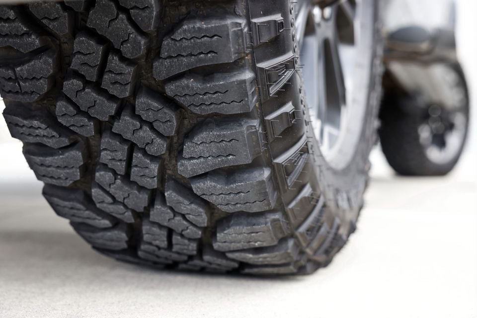 Close-up of a large mud-terrain tyre on a Ram 2500 Warlock, showing aggressive chunky tread pattern on a paved surface
