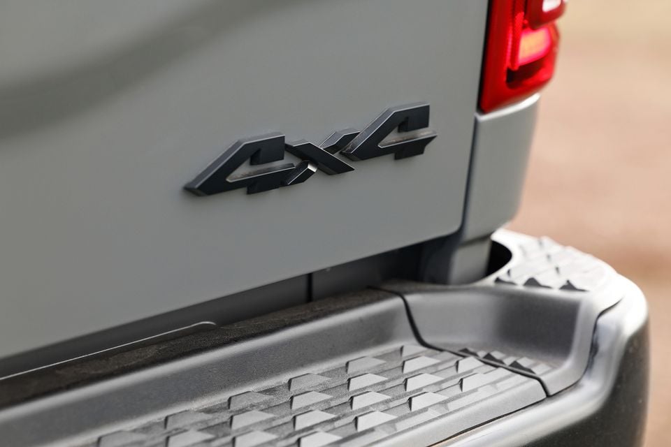Close-up of a "4x4" badge on the tailgate of a grey Ram 2500 pickup truck, with the rear step bumper visible below