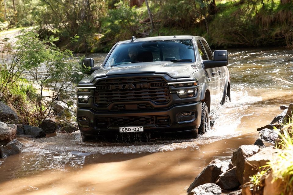 A grey Ram 2500 Warlock ute driving through a shallow river crossing surrounded by bushland
