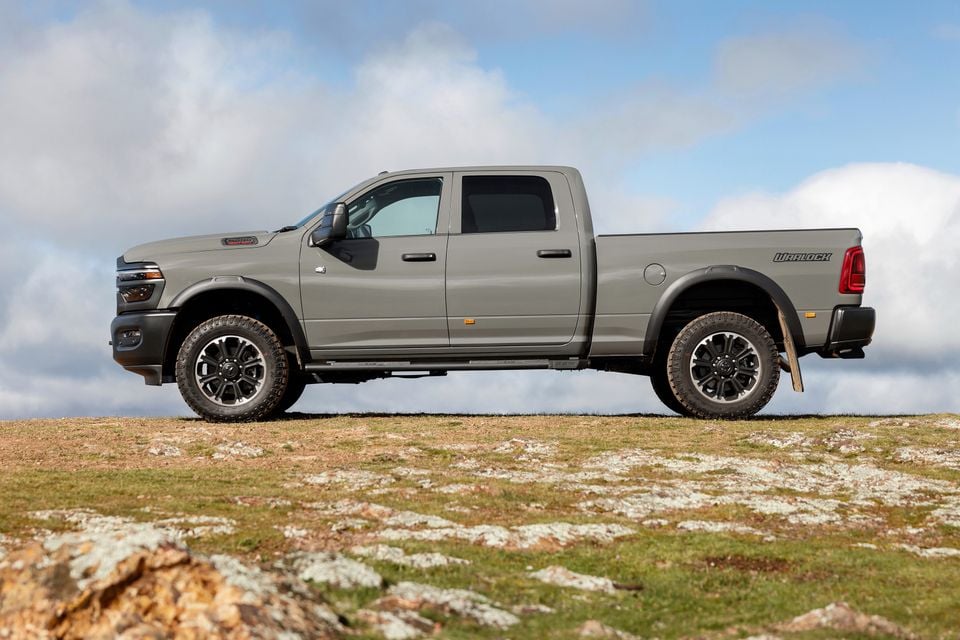 A grey Ram 2500 Warlock pickup truck seen from the side, parked on a rocky hilltop against a cloudy sky