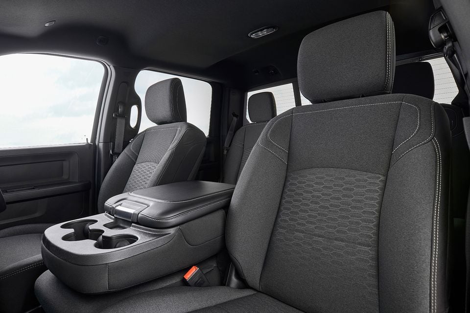 Interior view of a Ram 2500 Warlock showing dark fabric front seats with hexagonal stitching pattern, centre console with cup holders, and rear seating area