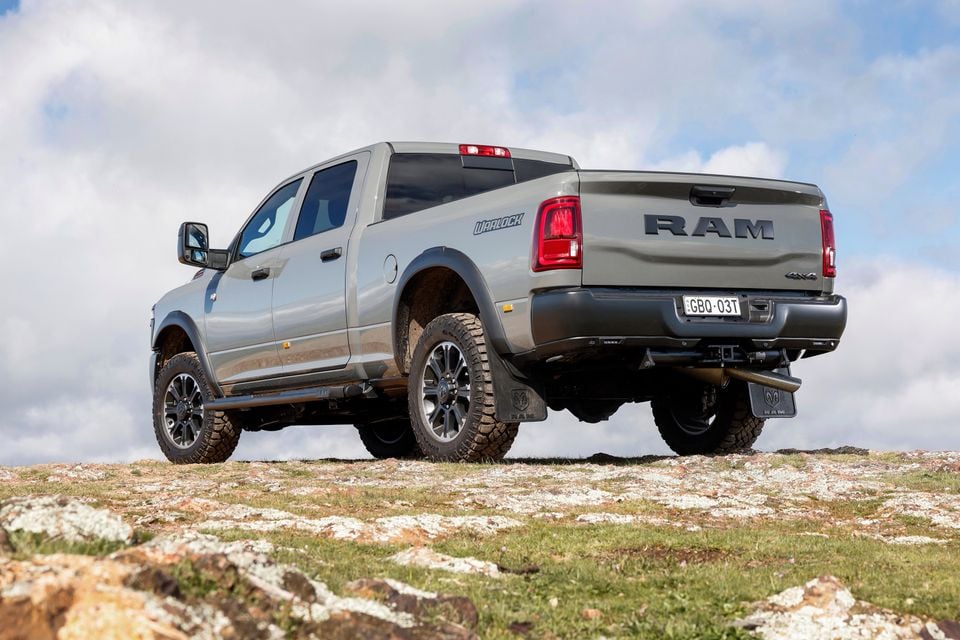 A silver Ram 2500 Warlock 4x4 pickup truck, seen from the rear quarter, parked on a rocky outcrop under a cloudy sky